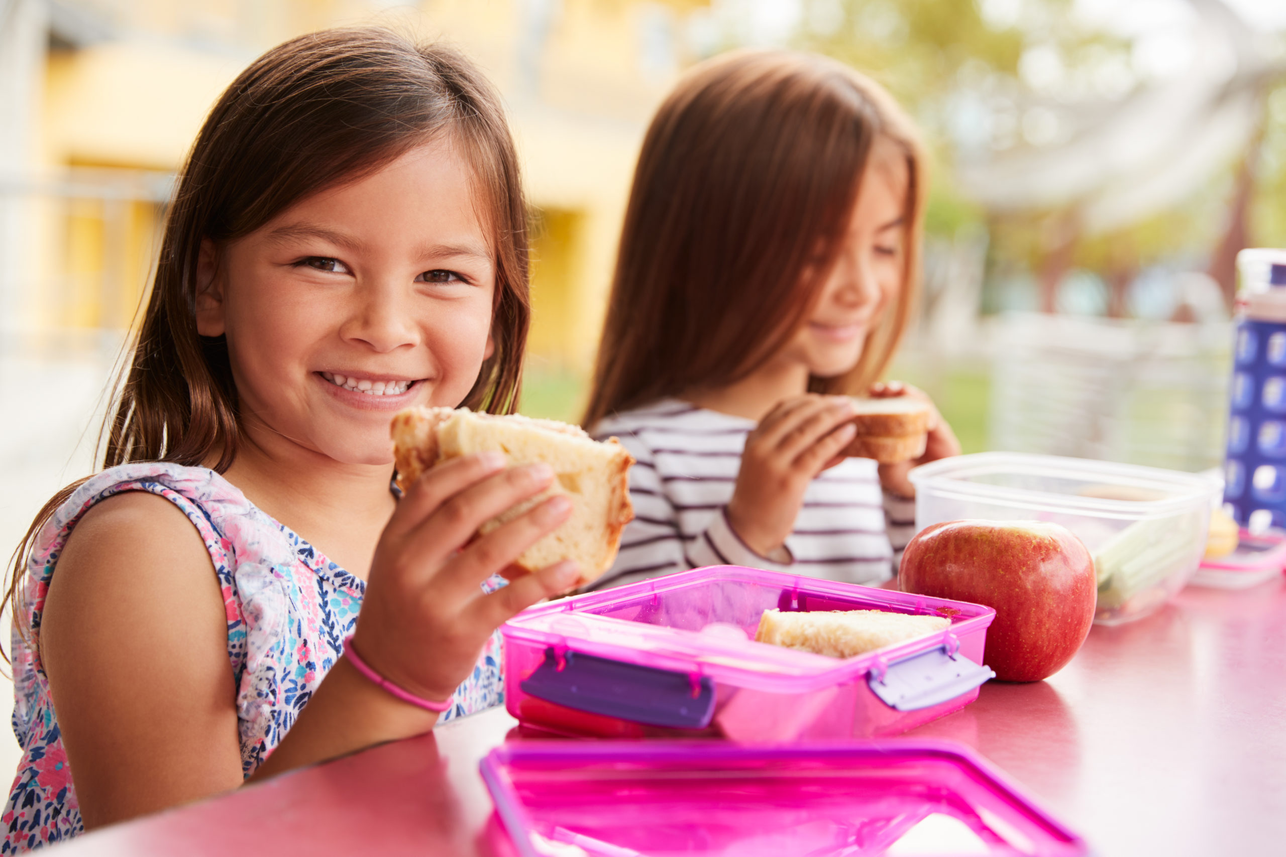Young,Schoolgirls,Holding,Sandwiches,At,School,Lunch,Table